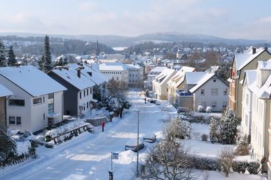 Blick in eine Straße mit Wohnhäusern, alles ist weiß mit Schnee bedeckt.