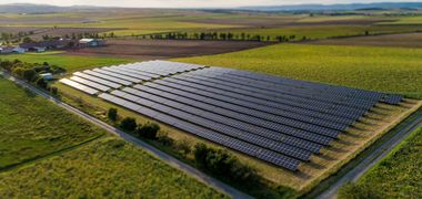 Luftaufnahme von einem Solarpark umgeben von Wiesen