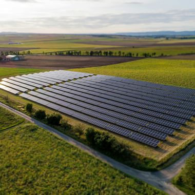 Luftaufnahme von einem Solarpark umgeben von Wiesen