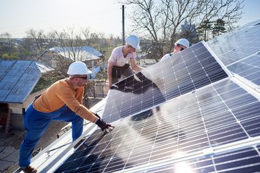 Arbeiter installieren Solarpaneele auf einem Dach