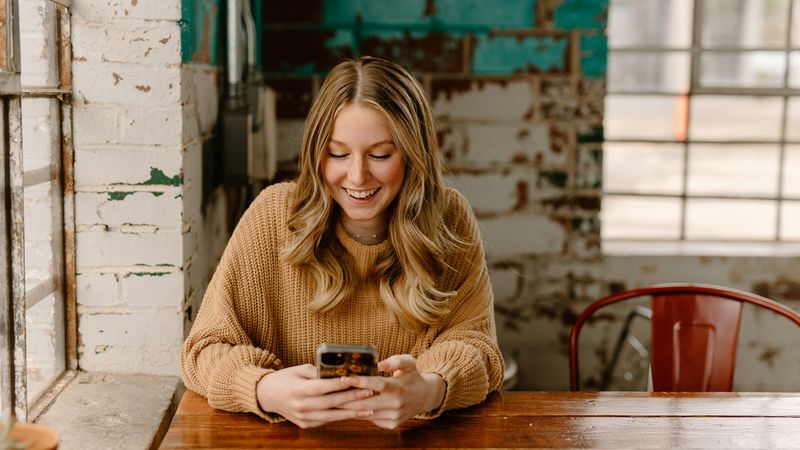 A woman reading on her phone at a café table