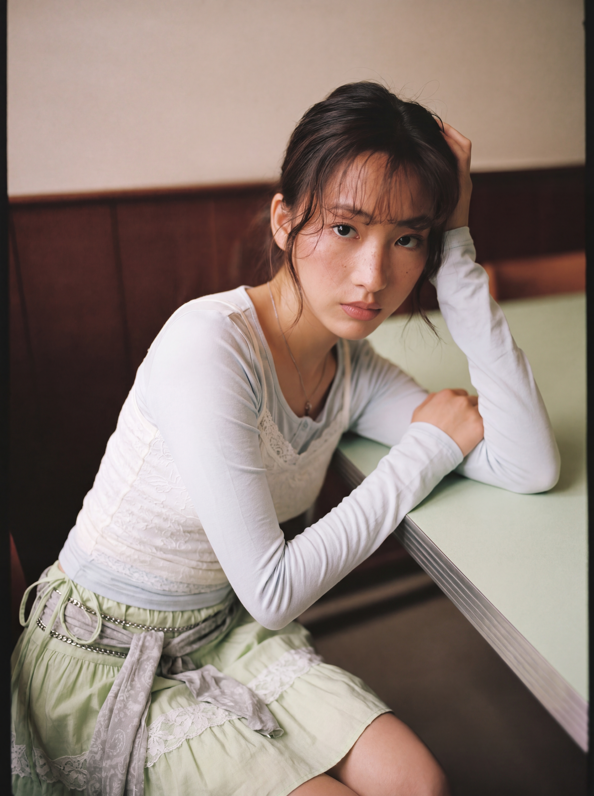 Change the outfit in this photo to: a fitted white long-sleeve top with lace trim layered over a white tank, paired with a low-rise pastel mint green tiered mini skirt with white lace details and a grey lace fabric tied around the waist.