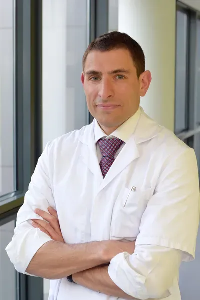 Man in a white lab coat with arms crossed.