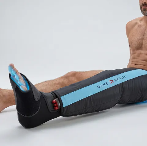 A man is sitting down with a Game Ready wrap around his entire left leg.