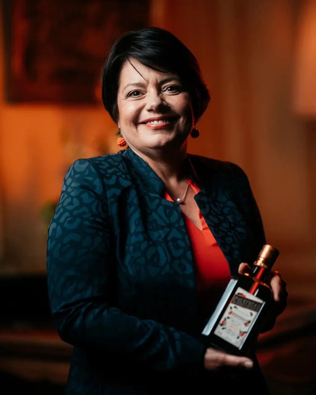 A medium close-up of Carole Quinton, master distiller at Cointreau with a bottle of Cointreau Orange liqueur