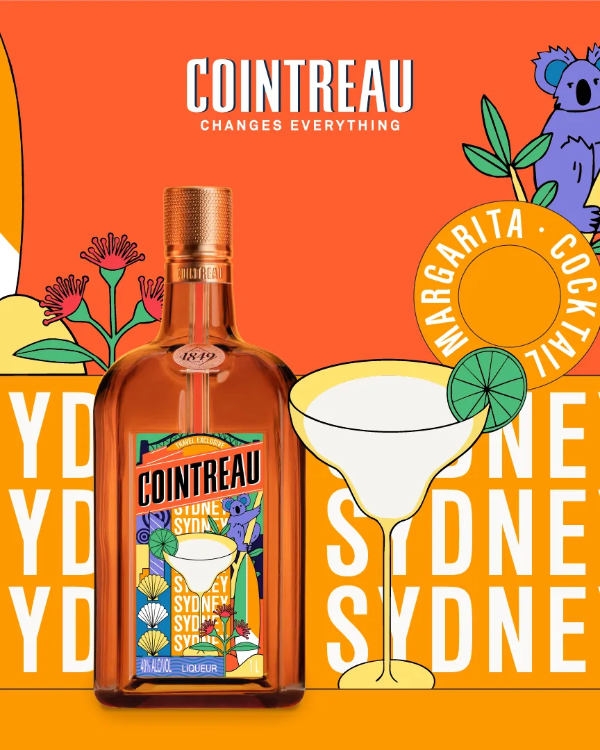 Cointreau bottle in the center with three people leaning in from above against a bright blue sky background.