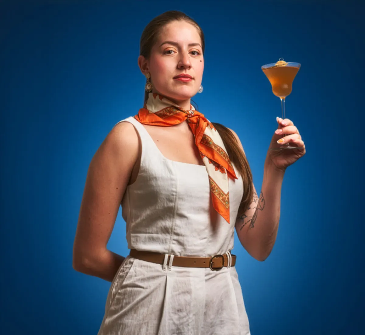 Mixologist holding a cocktail glass in front of a blue background