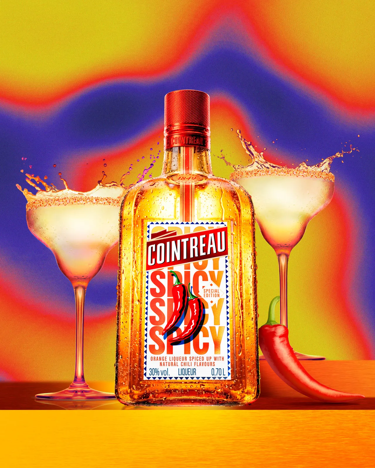 Cointreau Spicy bottle with chilli graphic centred between two margarita glasses, splashes and red chilli on vibrant gradient background