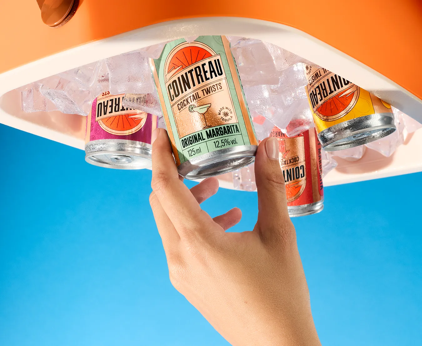 Cointreau ready‑to‑drink cocktail cans in ice, hand selecting margarita flavour