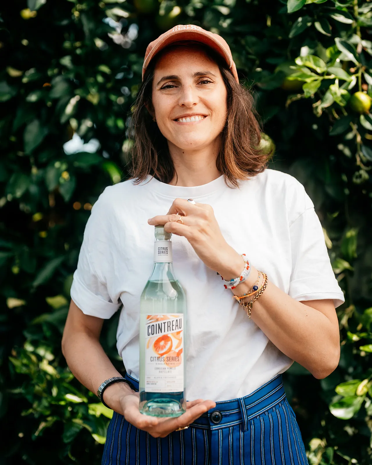 Portrait pour Cointreau Cocktail Talks, représentant une personne tenant une bouteille de Cointreau Citrus Series dans un verger d'agrumes.