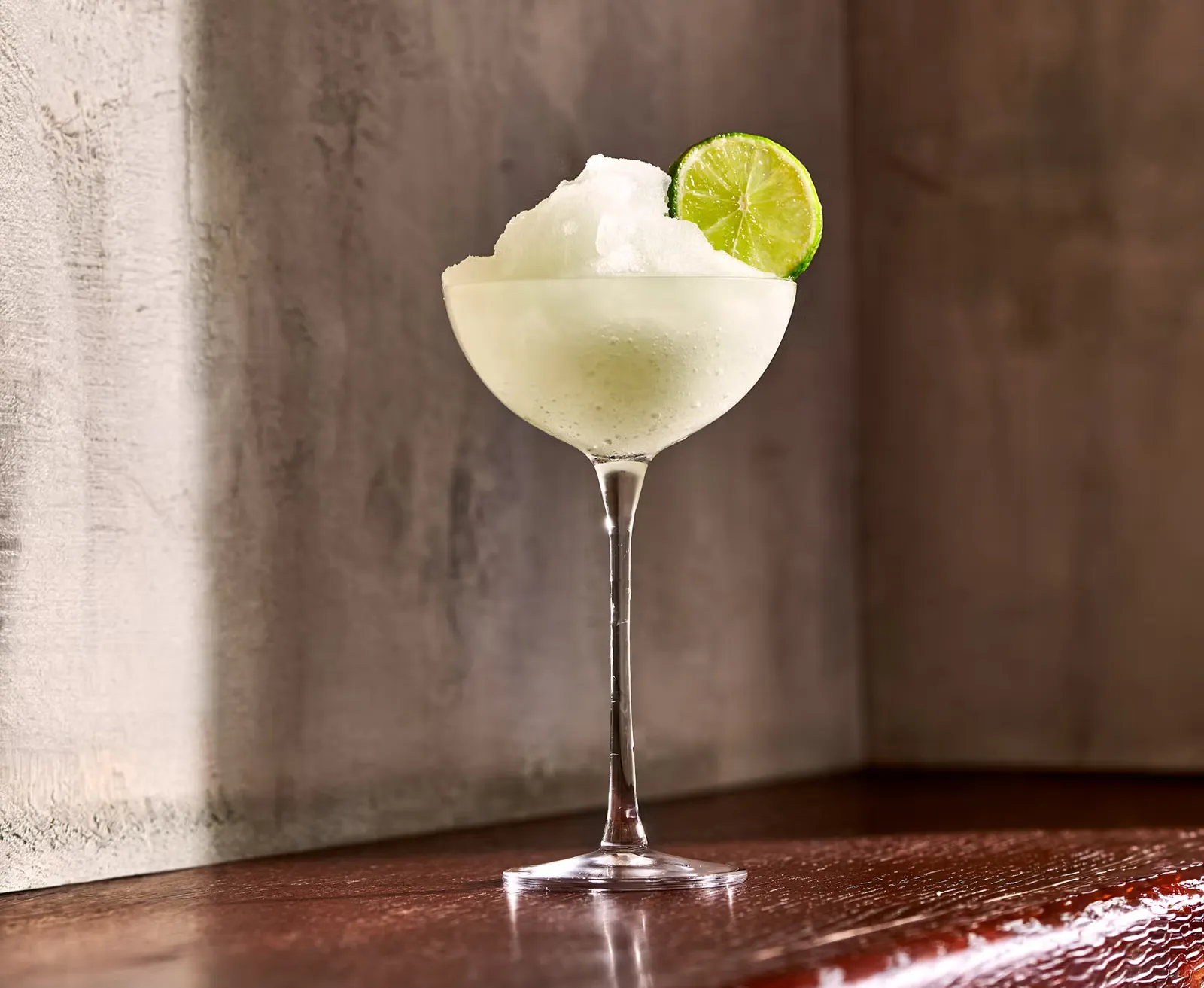 A Frozen Margarita Cocktail in front of a structured wall