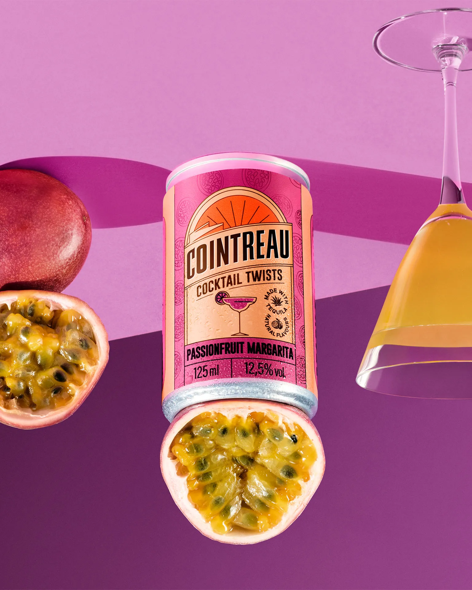Cointreau Passionfruit Margarita can with fresh passionfruit and cocktail glass on violet background