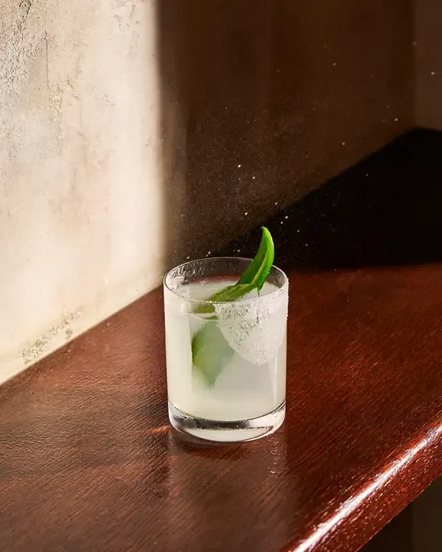 Spicy Margarita with lime garnish and salted rim in a rocks glass on a wooden bar