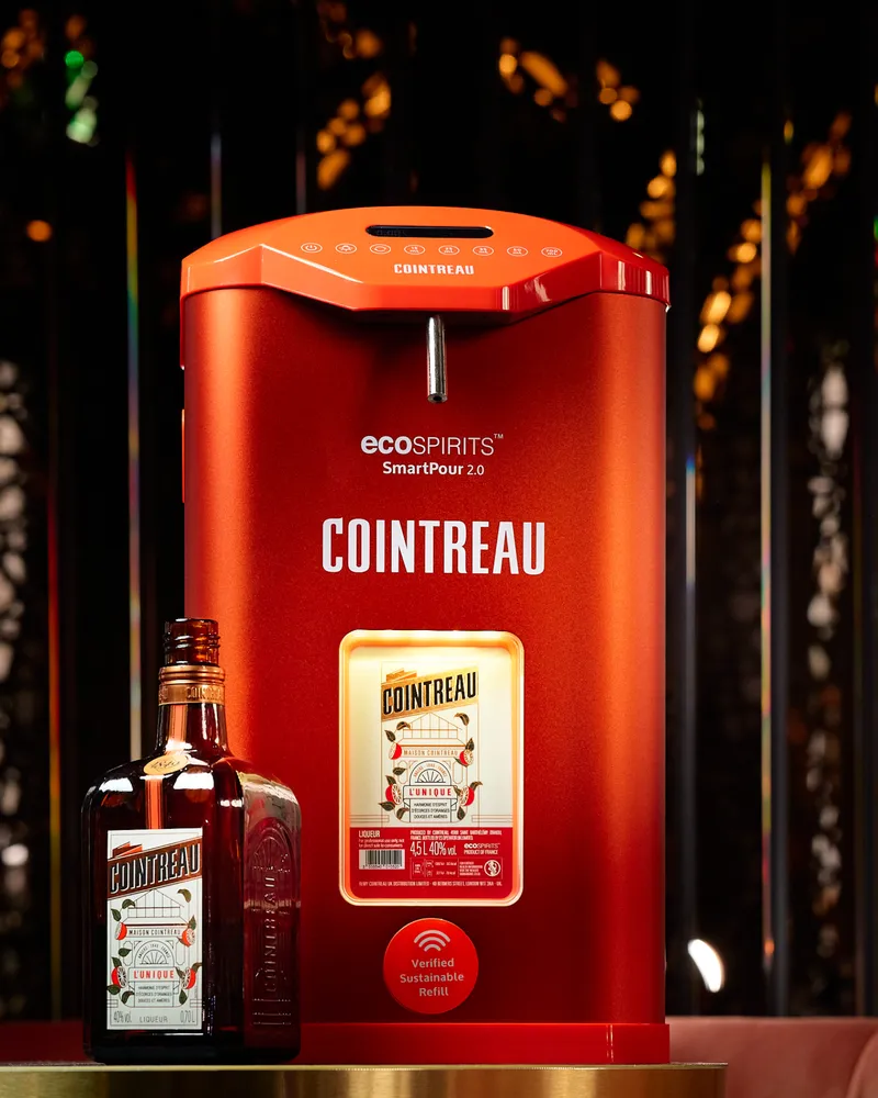 Cointreau bottle positioned next to a Cointreau SmartPour 2.0 refill station, highlighting the sustainable refill system in a bar environment.