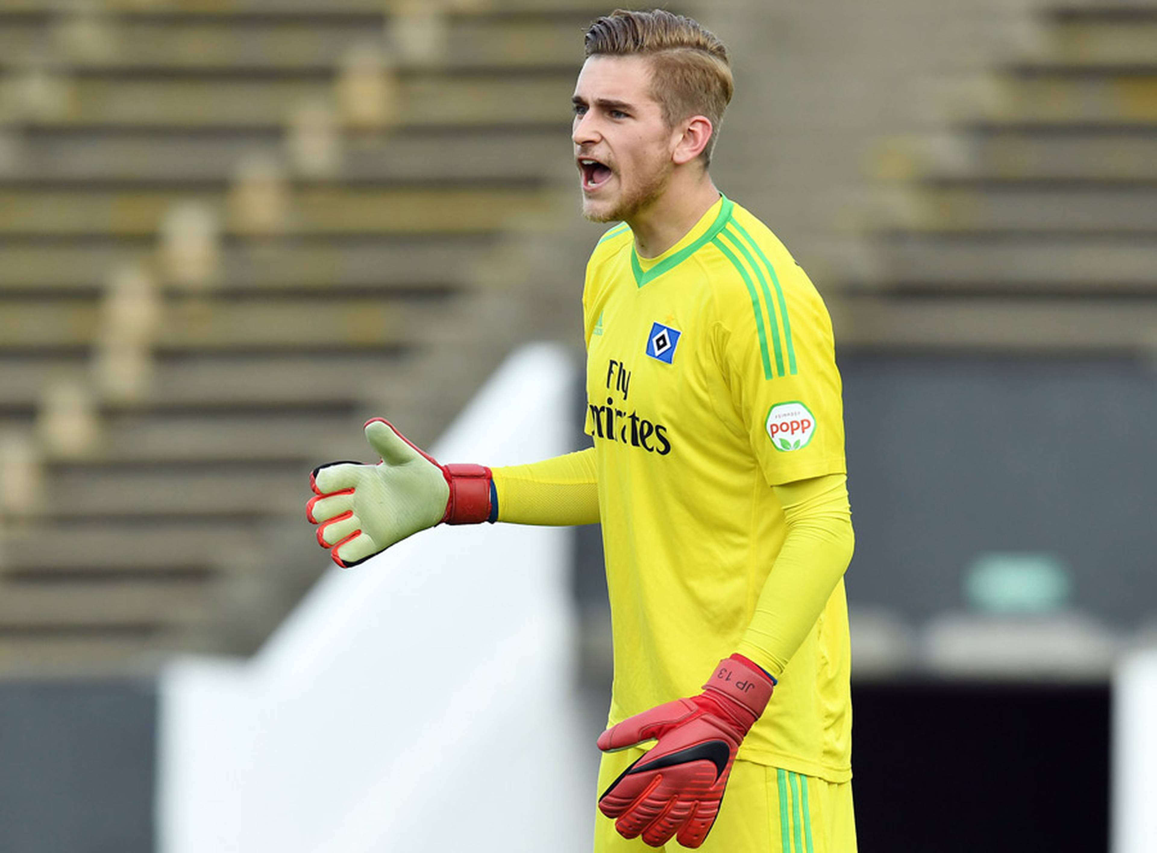 Julian Pollersbeck steht im Testspiel gegen Freiburg auf dem Rasen und ruft etwas zu seinen Vorderleuten.