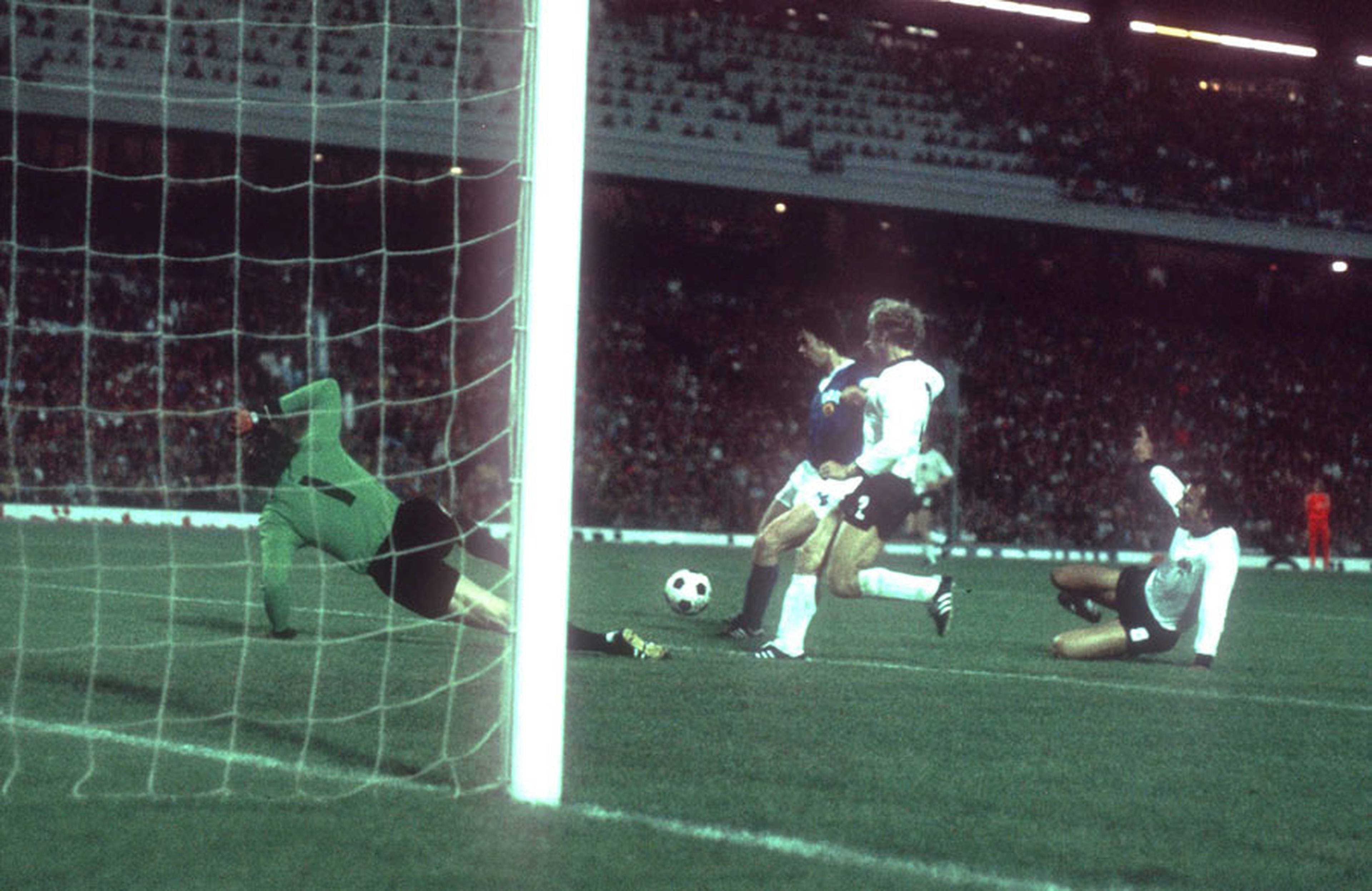 Jürgen Sparwasser pushes past defender Berti Vogts as goalkeeper Sepp Maier looks on.