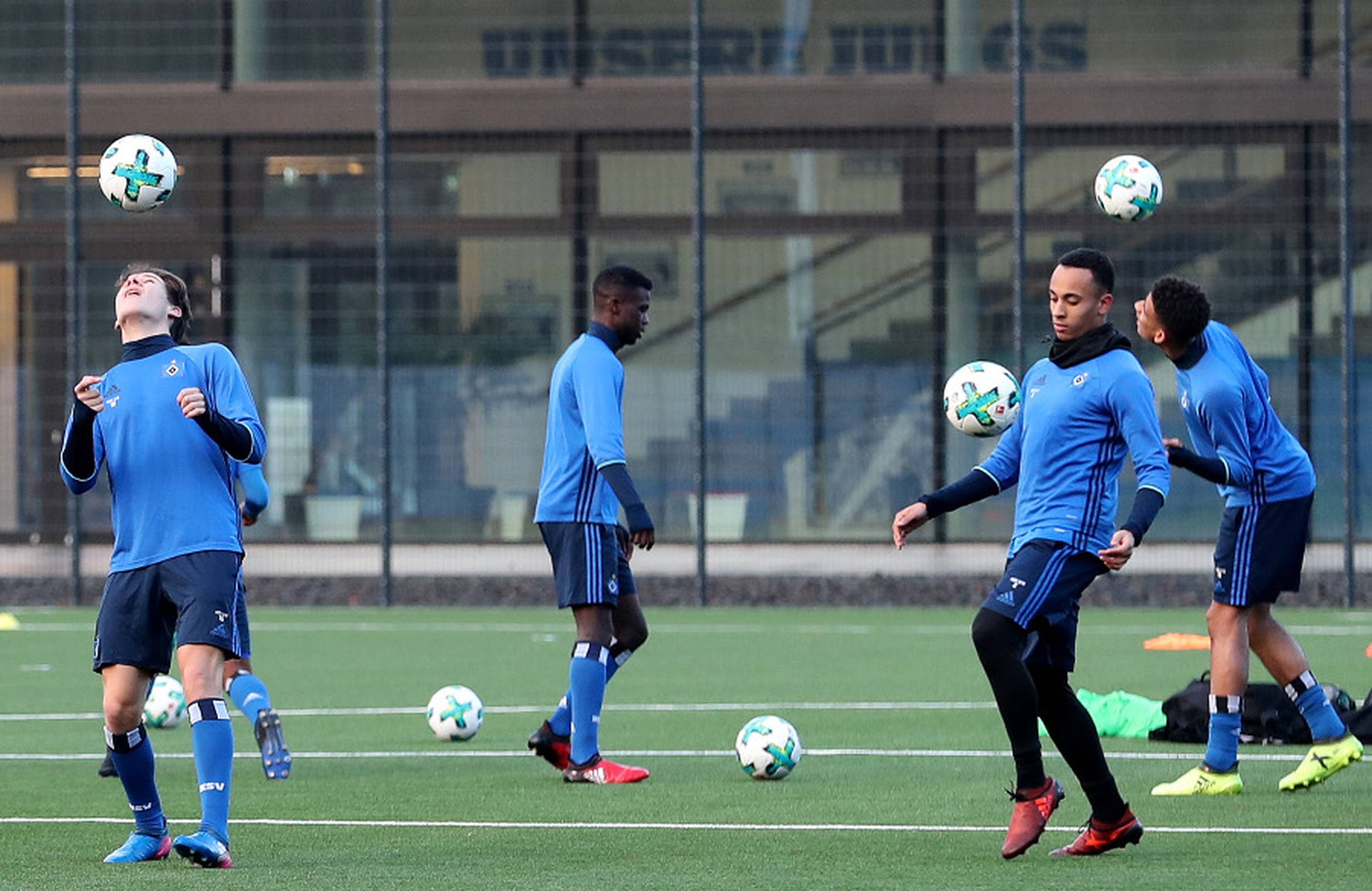 Vier U19-Spieler versuchen auf dem Trainingsplatz, den Ball mit der gesamten Körperfläche hochzuhalten.
