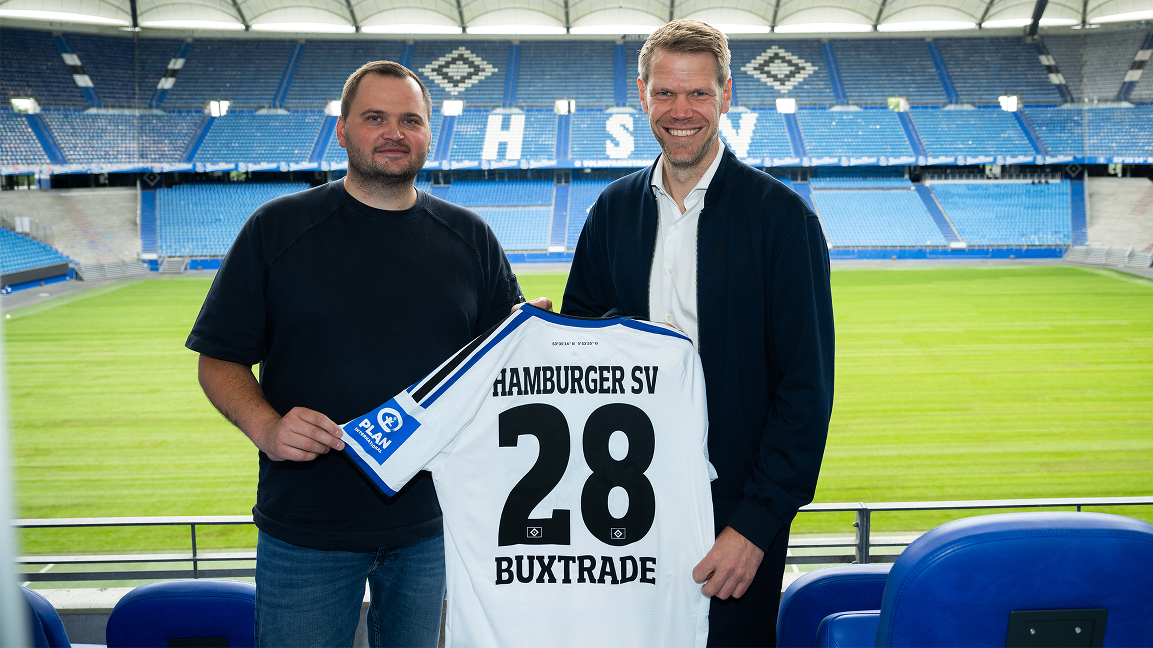 CEO von Buxtrade GmbH und HSV-Vorstand Eric Huwer halten ein Trikot mit der Aufschrift "Buxtrade" in den Händen und lächeln in die Kamera.