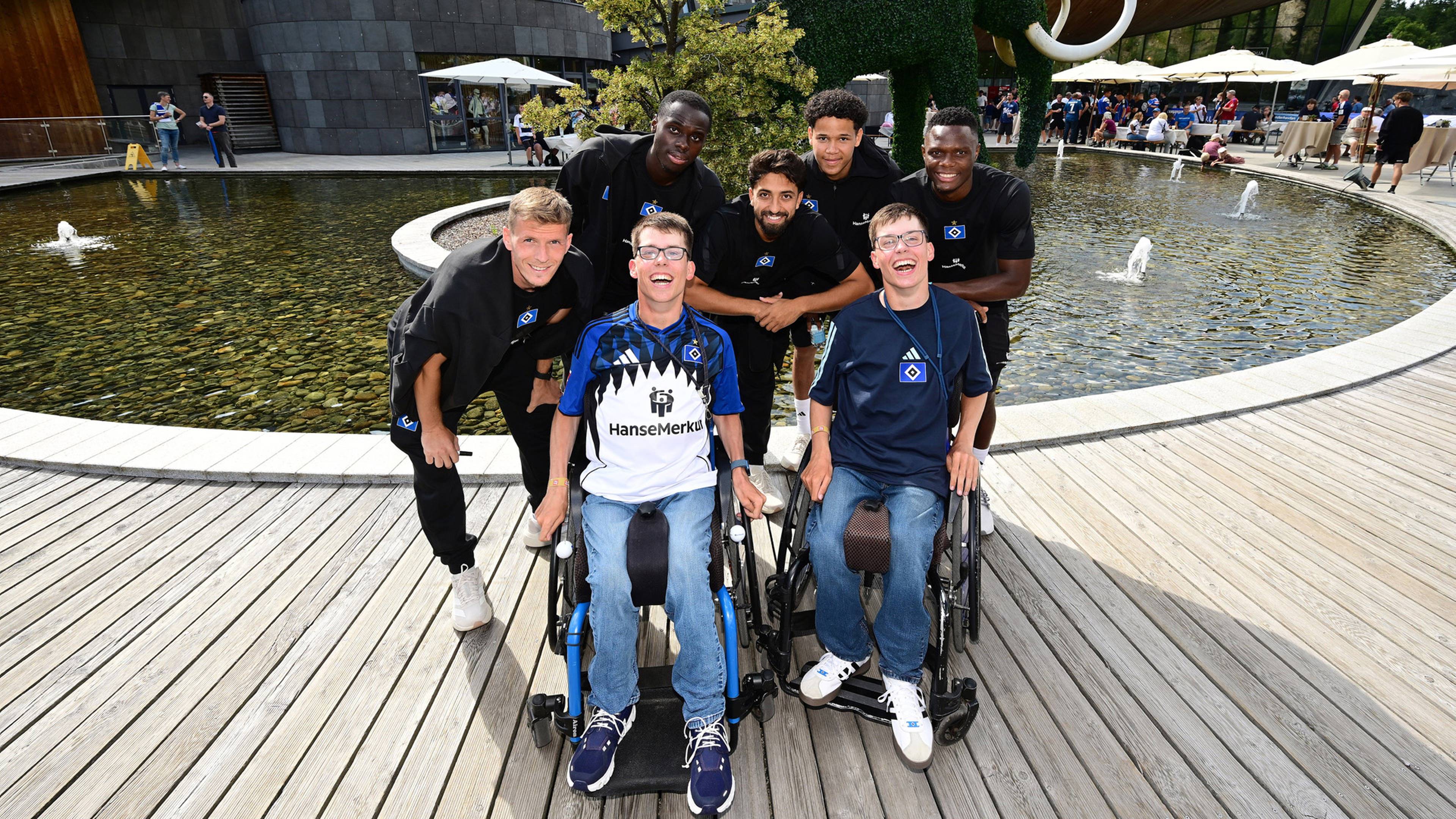 Die beiden Fricke-Brüder im Rollstuhl posieren mit HSV-Profis für ein gemeinsames Foto im Trainingslager