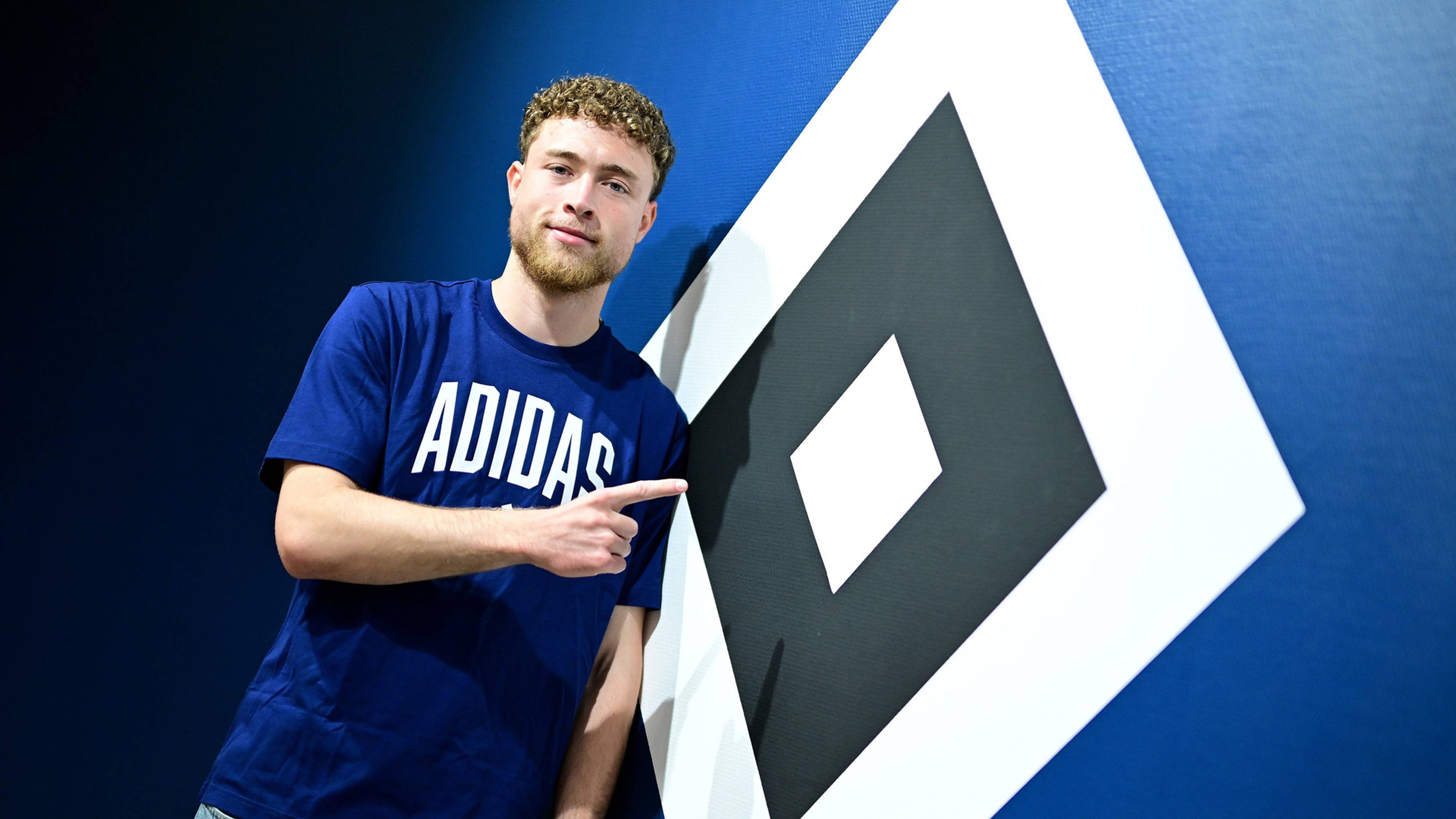 Hannes Hermann zeigt auf die HSV-Raute, die eine Wand ziert