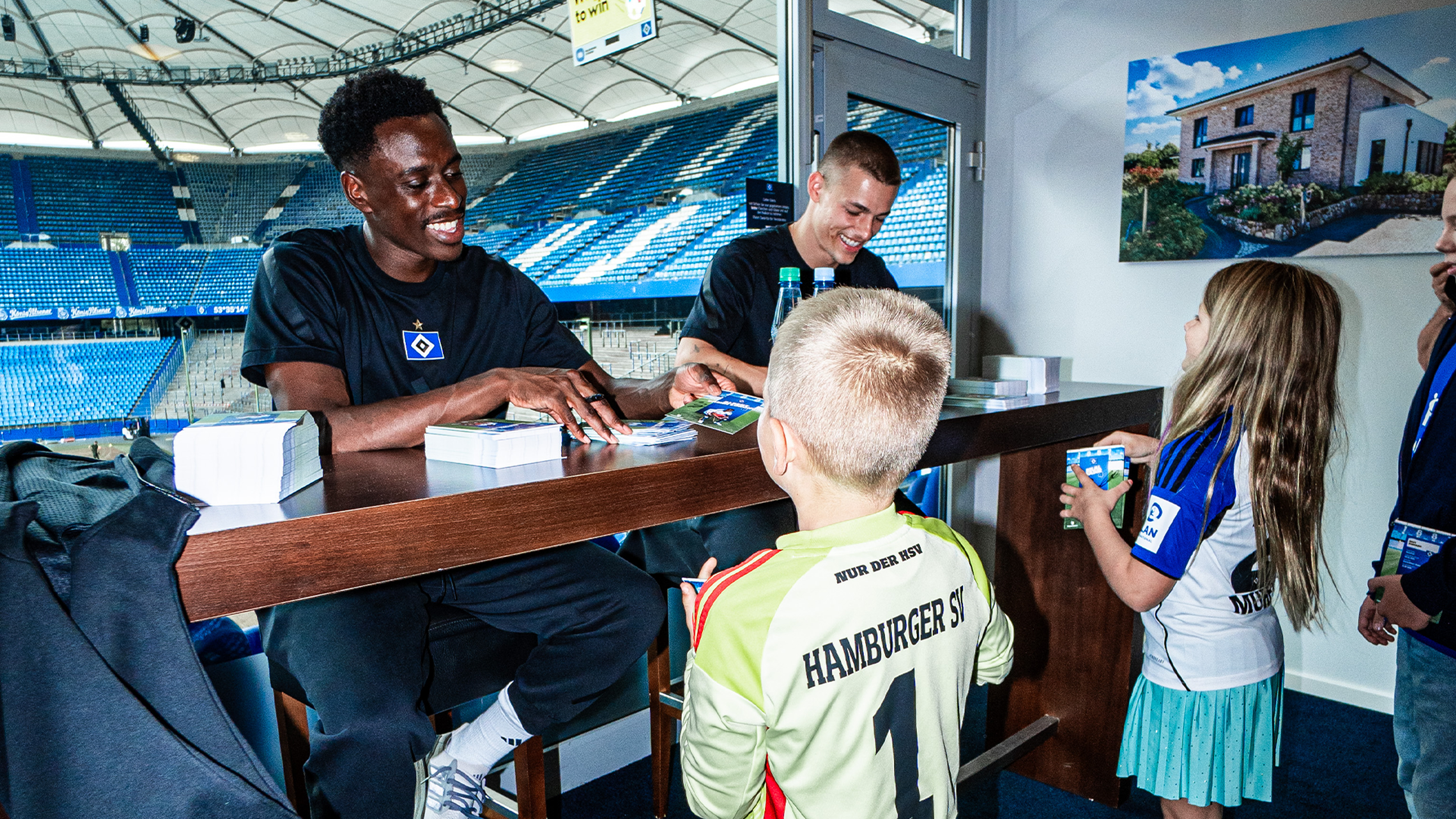 Zwei HSV-Spieler geben Autogramme an junge Fans.