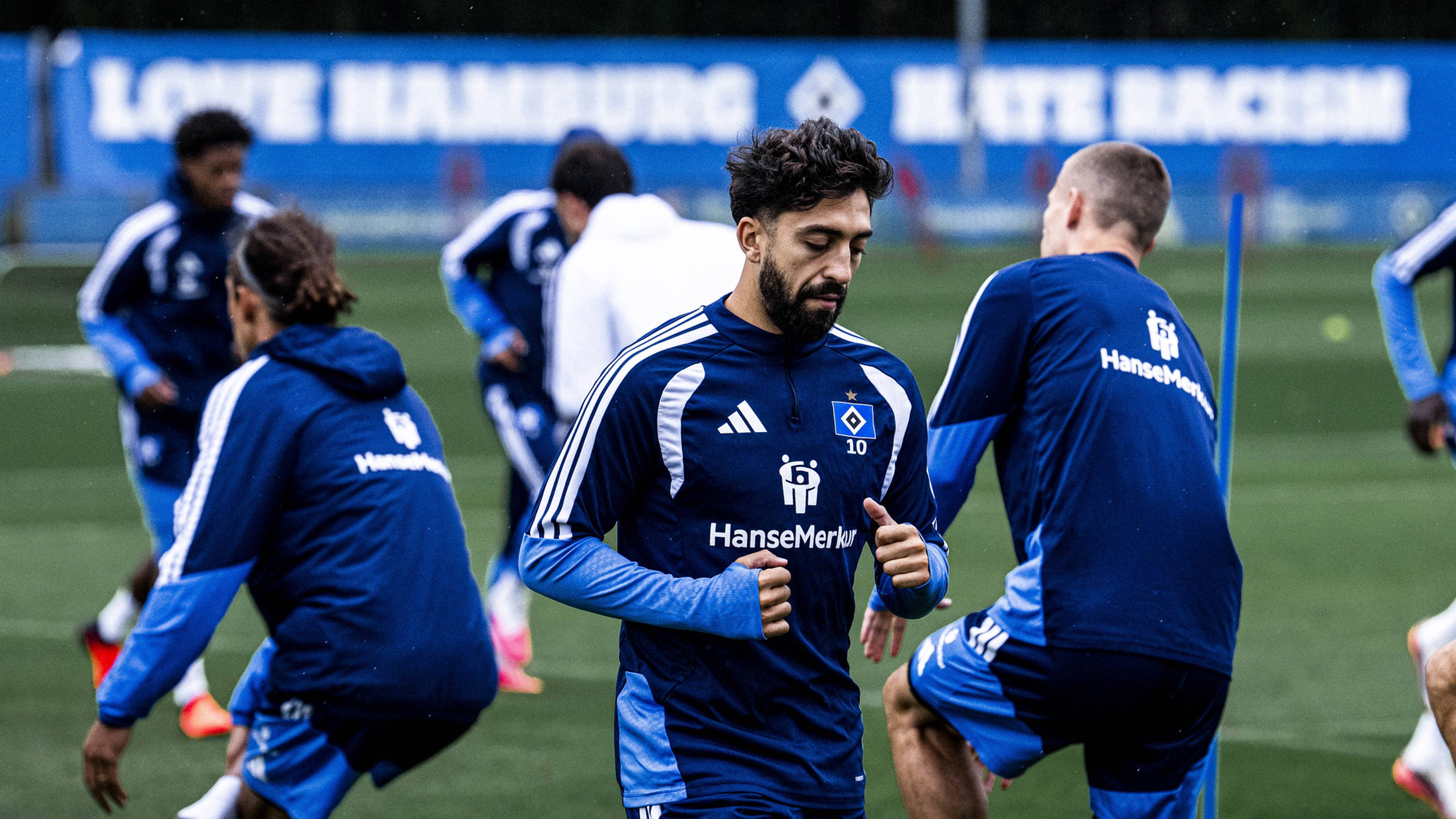 Immanuel Pherai beim Aufwärmen, im Hintergrund das "Love Hamburg Hate Racism"-Banner am Trainingsgelände