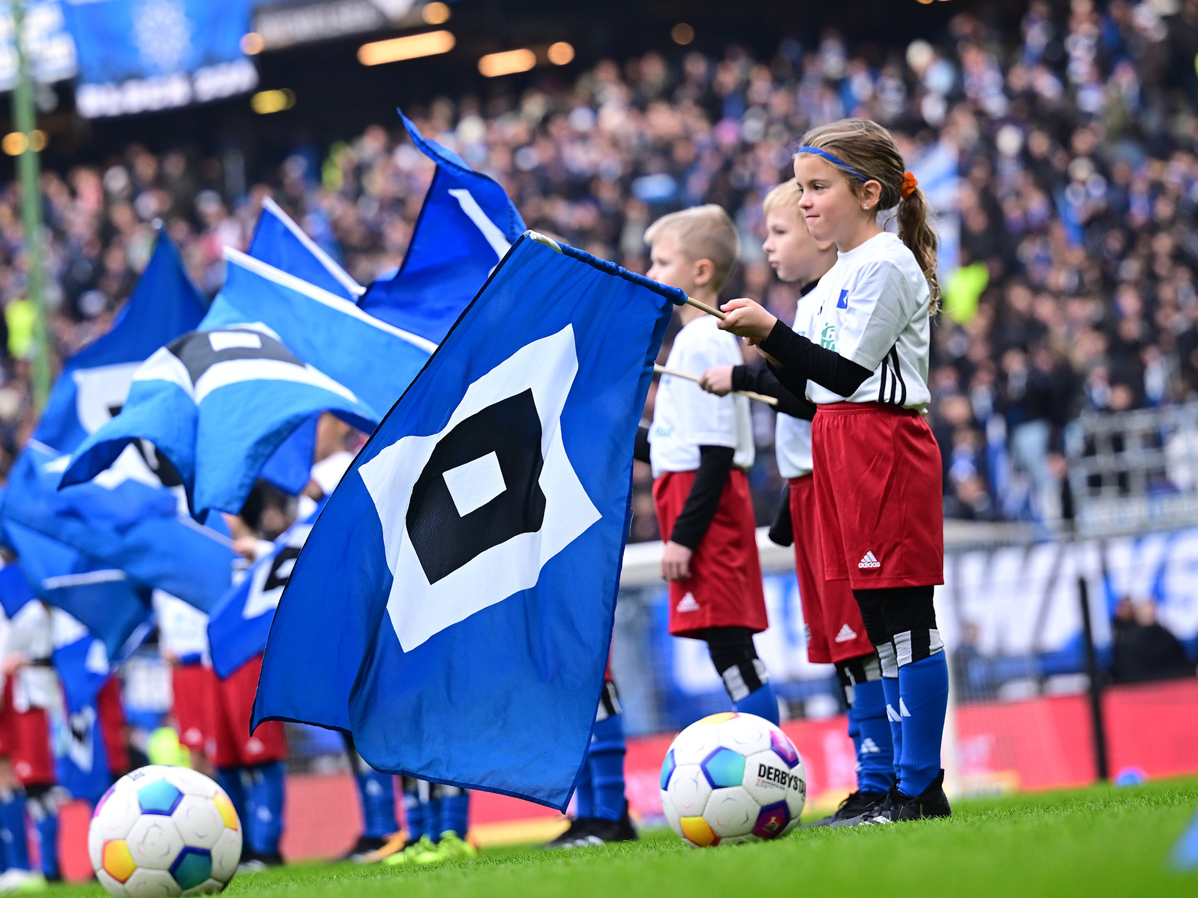 Einlaufkind beim Heimspiel, das eine Fahne hält