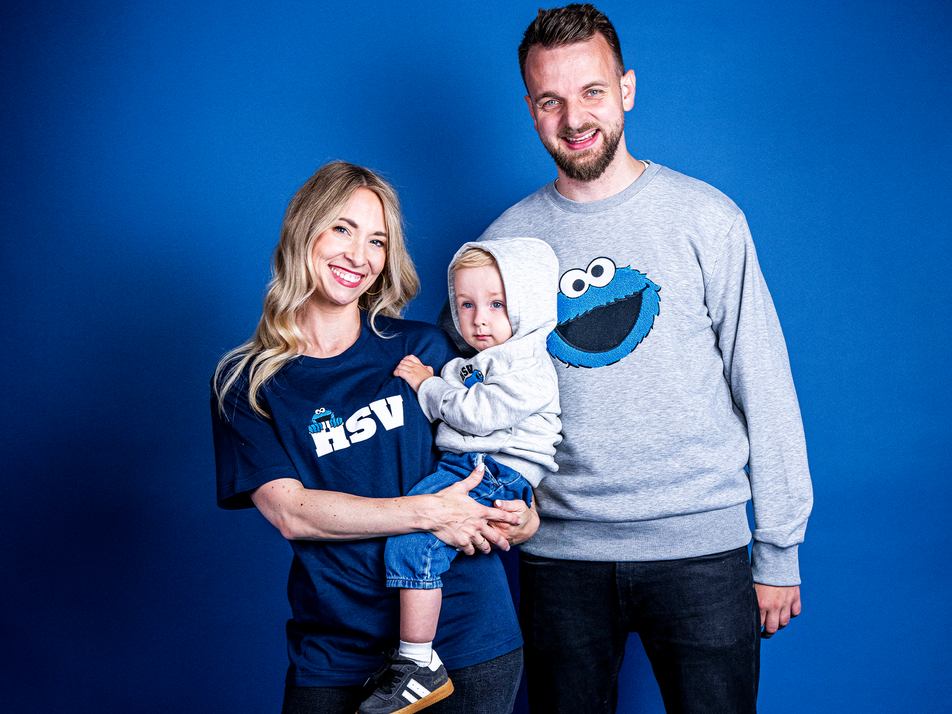 Wir sehen eine Familie mit dem neuen Merch in die Kamera lächeln.