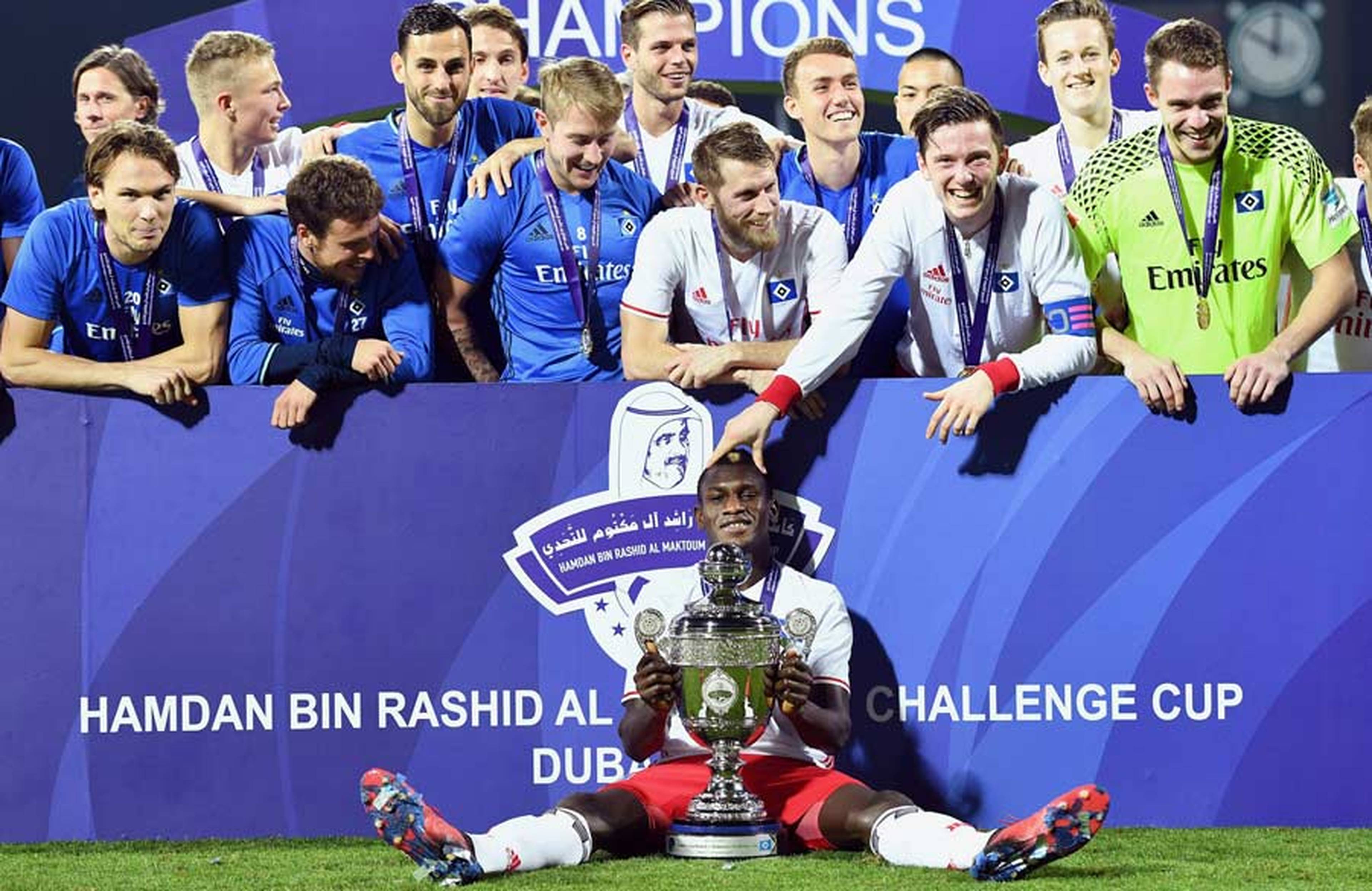 Bakery Jatta sitzt bei der Siegerehrung mit dem Pokal vor der Mannschaft.