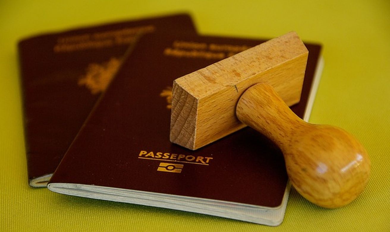 Deux passeports français en gros plan avec un tampon en bois sur fond vert.