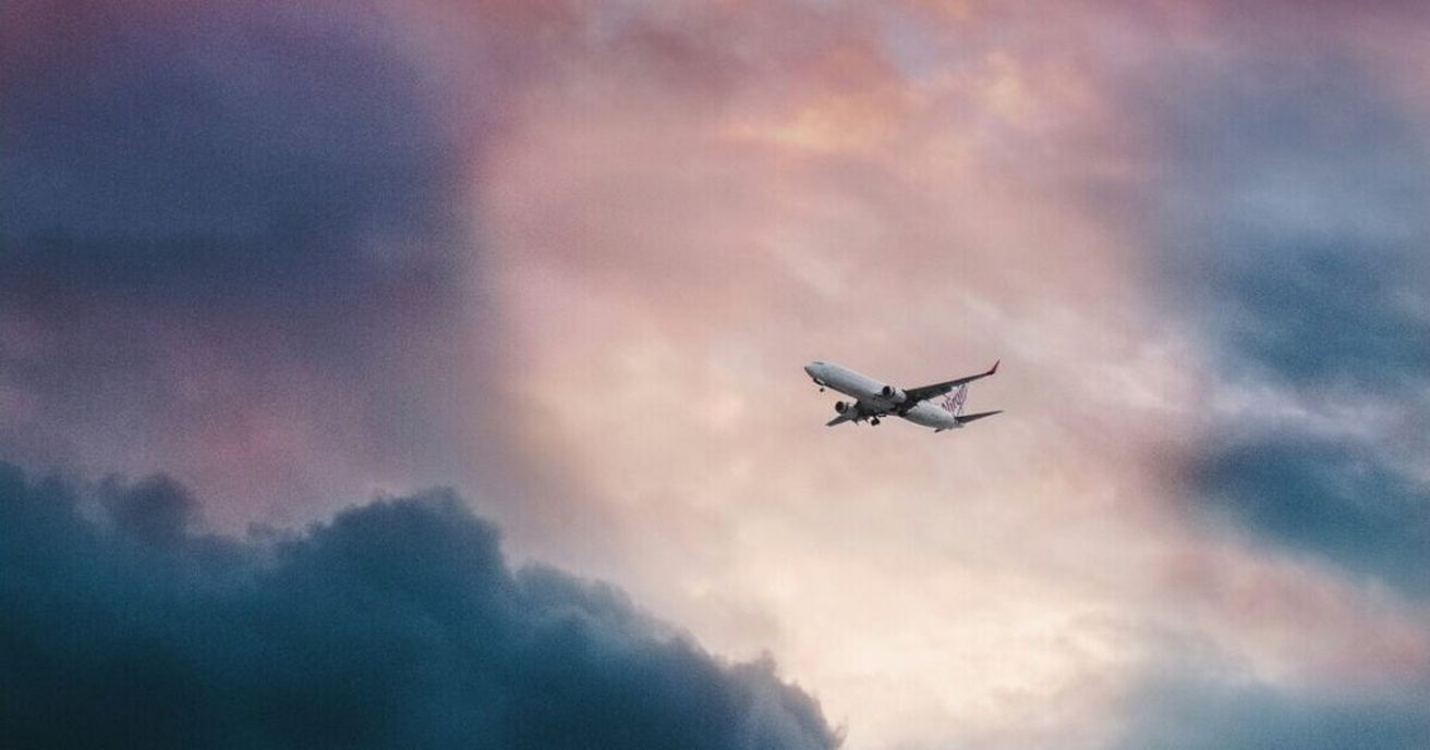 Ein Flugzeug fliegt in der Entfernung am rosa-roten Abendhimmel