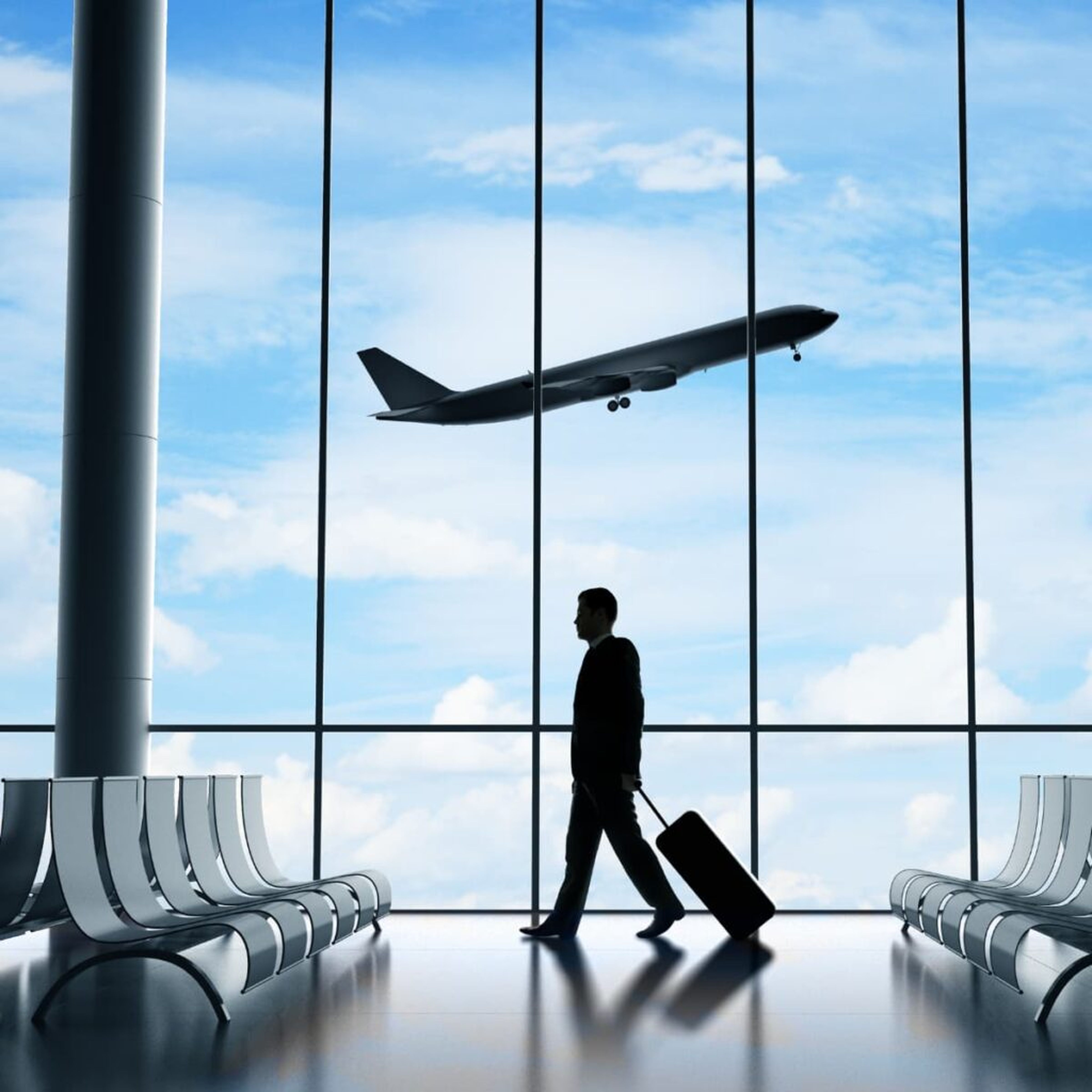 Person mit Koffer in Flughafenlounge, Flugzeug fliegt draußen.