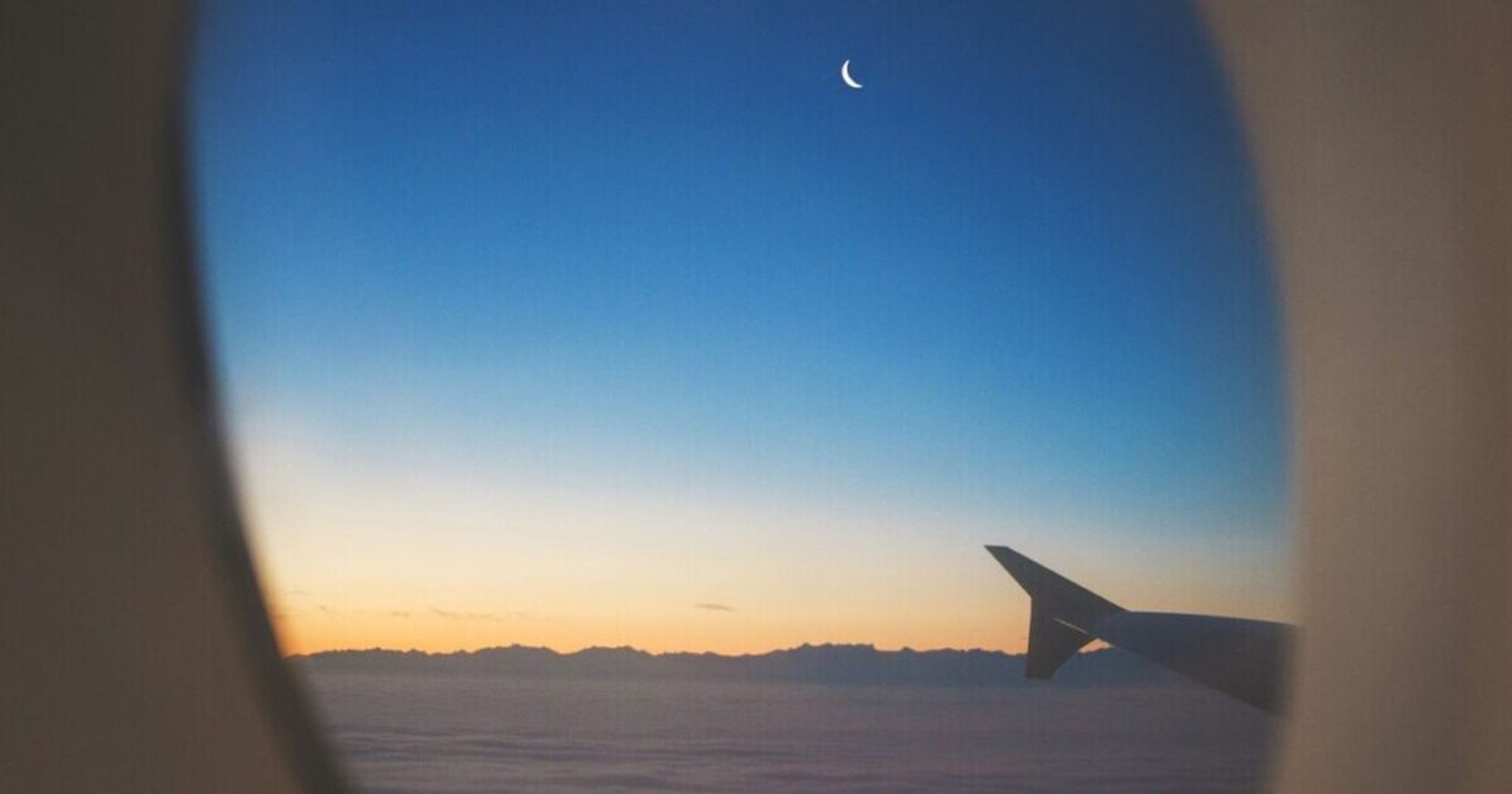Ein FLugzeug bei Nacht mit Halbmond am Himmel