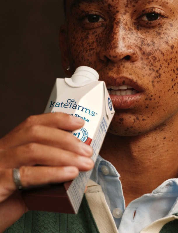 A young man holding a carton of Kate Farms shake