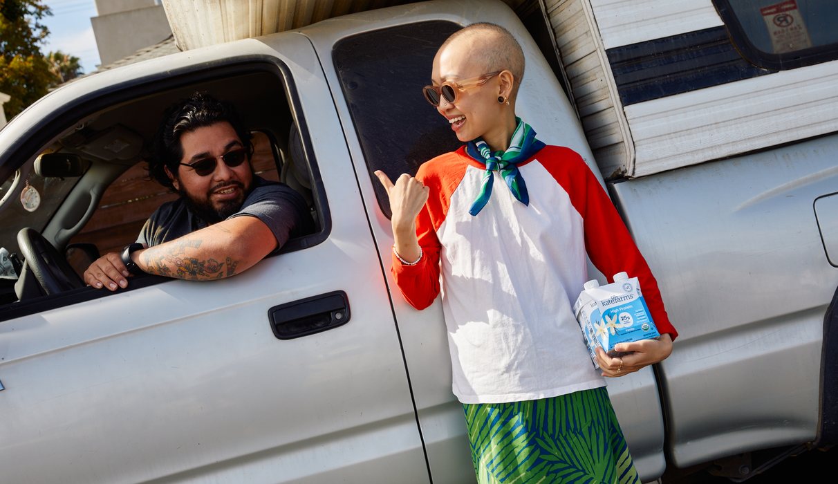 Anita holding a carton of Kate Farms beside a pickup truck