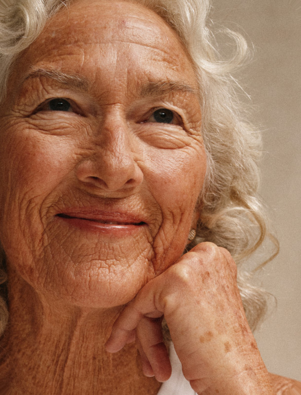 A smiling older woman resting her chin on her hand