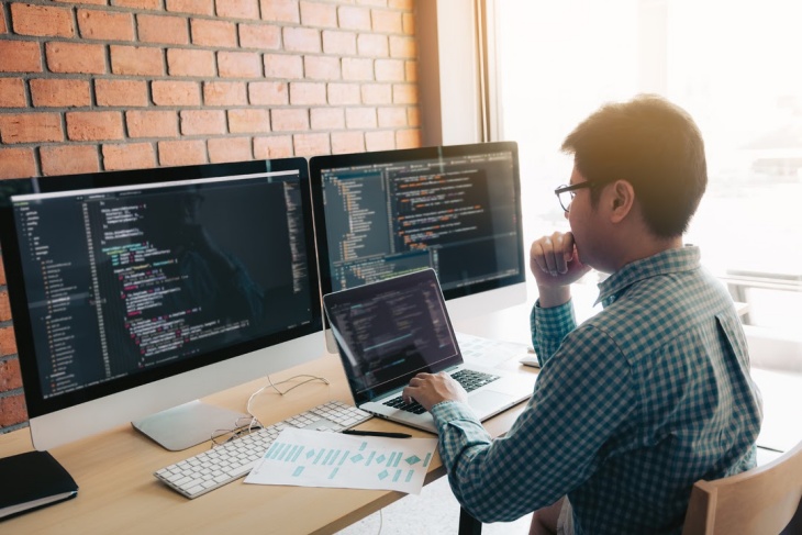 Working At A Desk With Three Computer Monitors