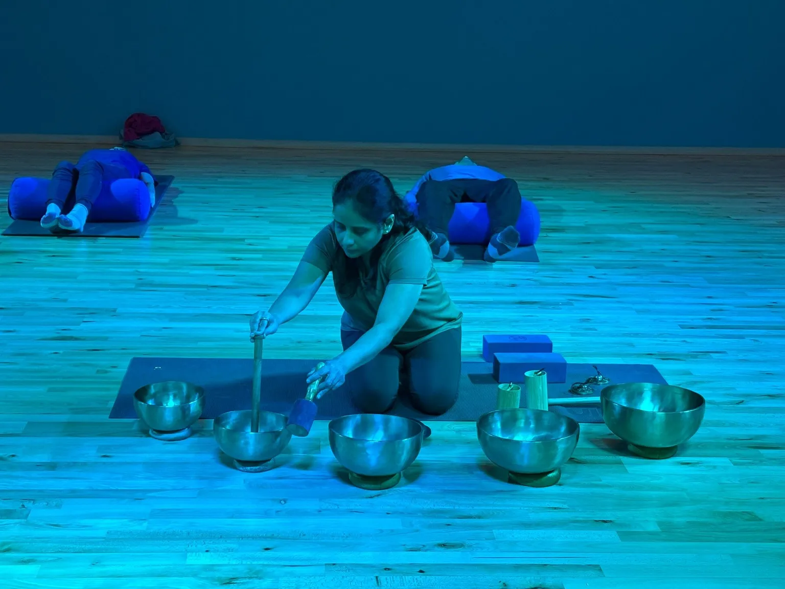 Class instructor in a Sound Bath class surrounding by sound bath bowls