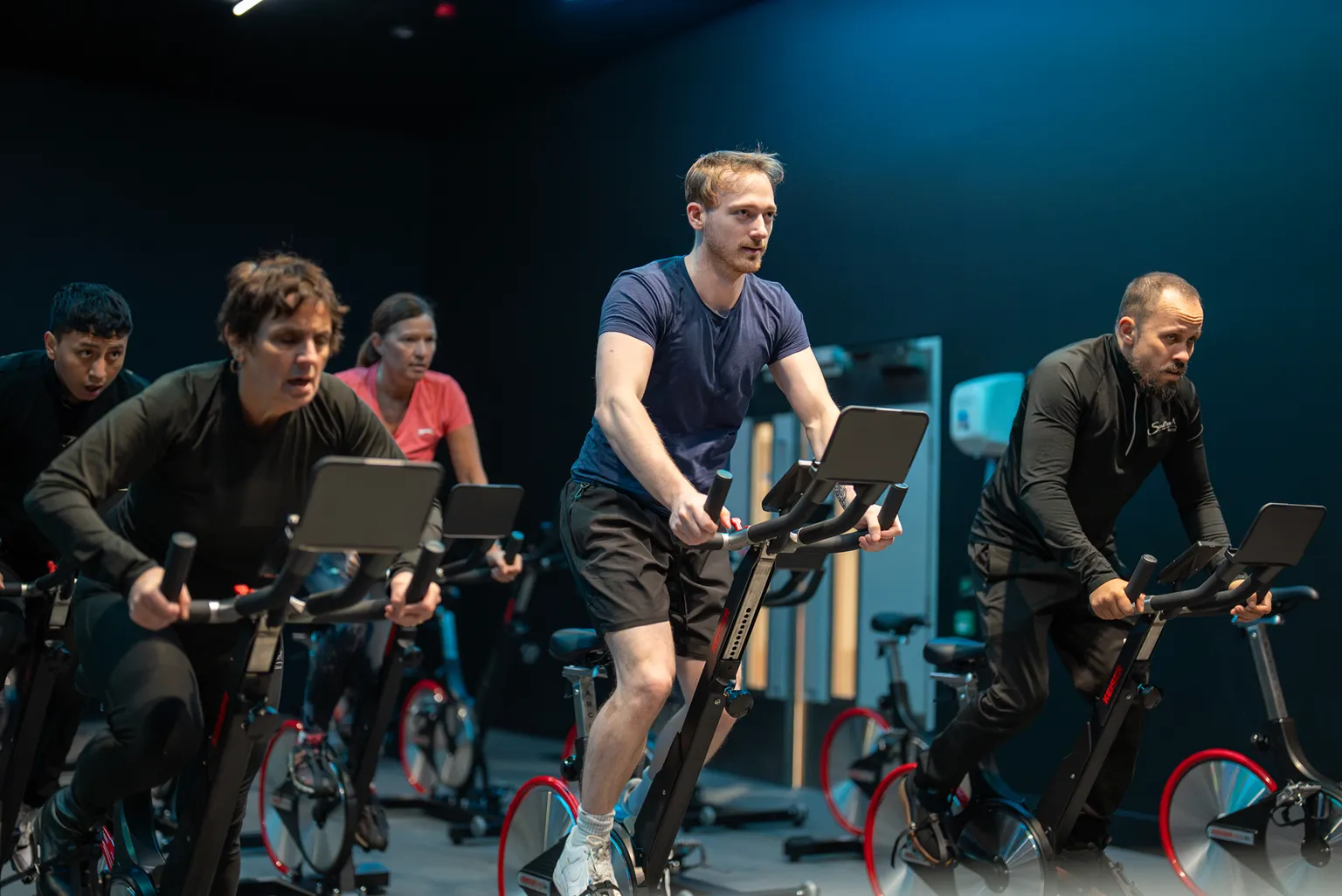 Group of focused individuals in a spin class, exercising on stationary bikes.