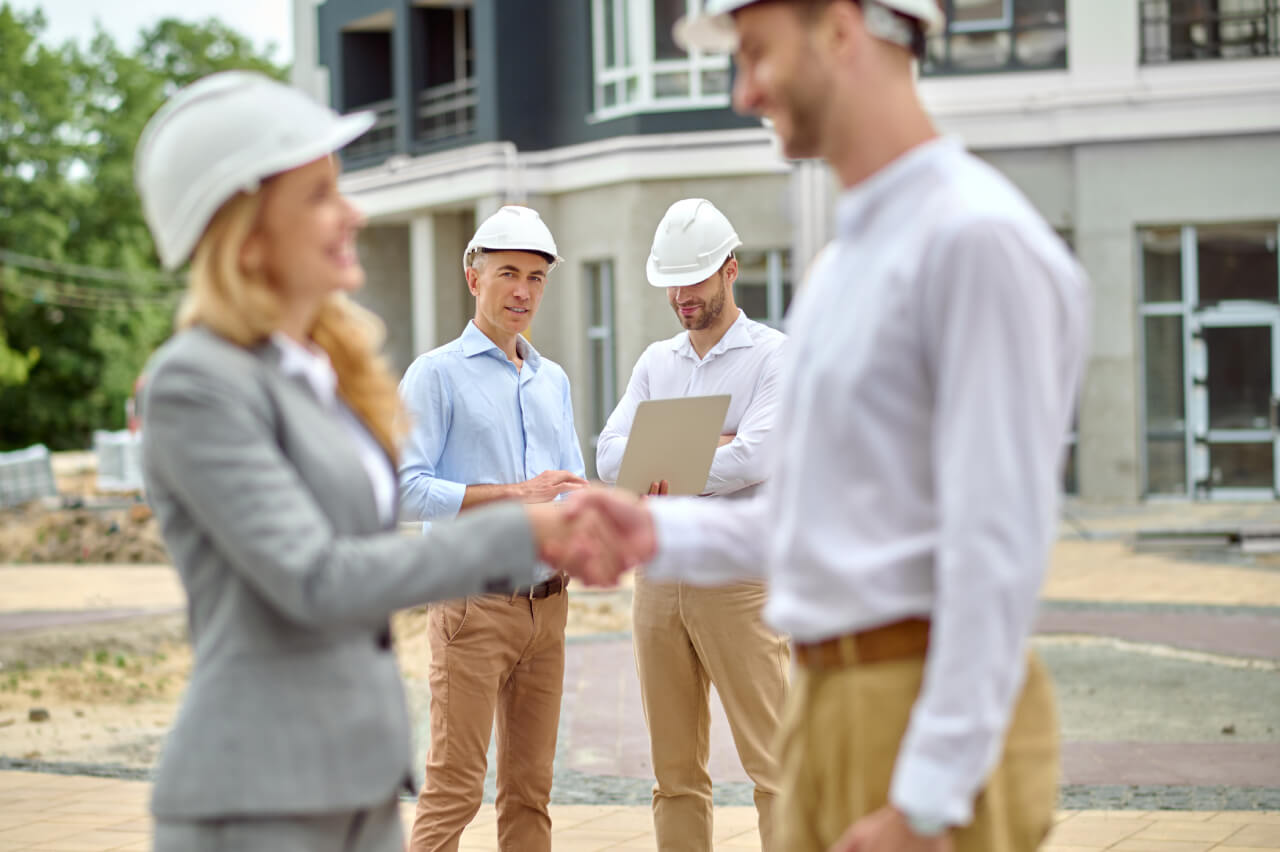 Két védősisakos építőipari szakember kezet ráz.