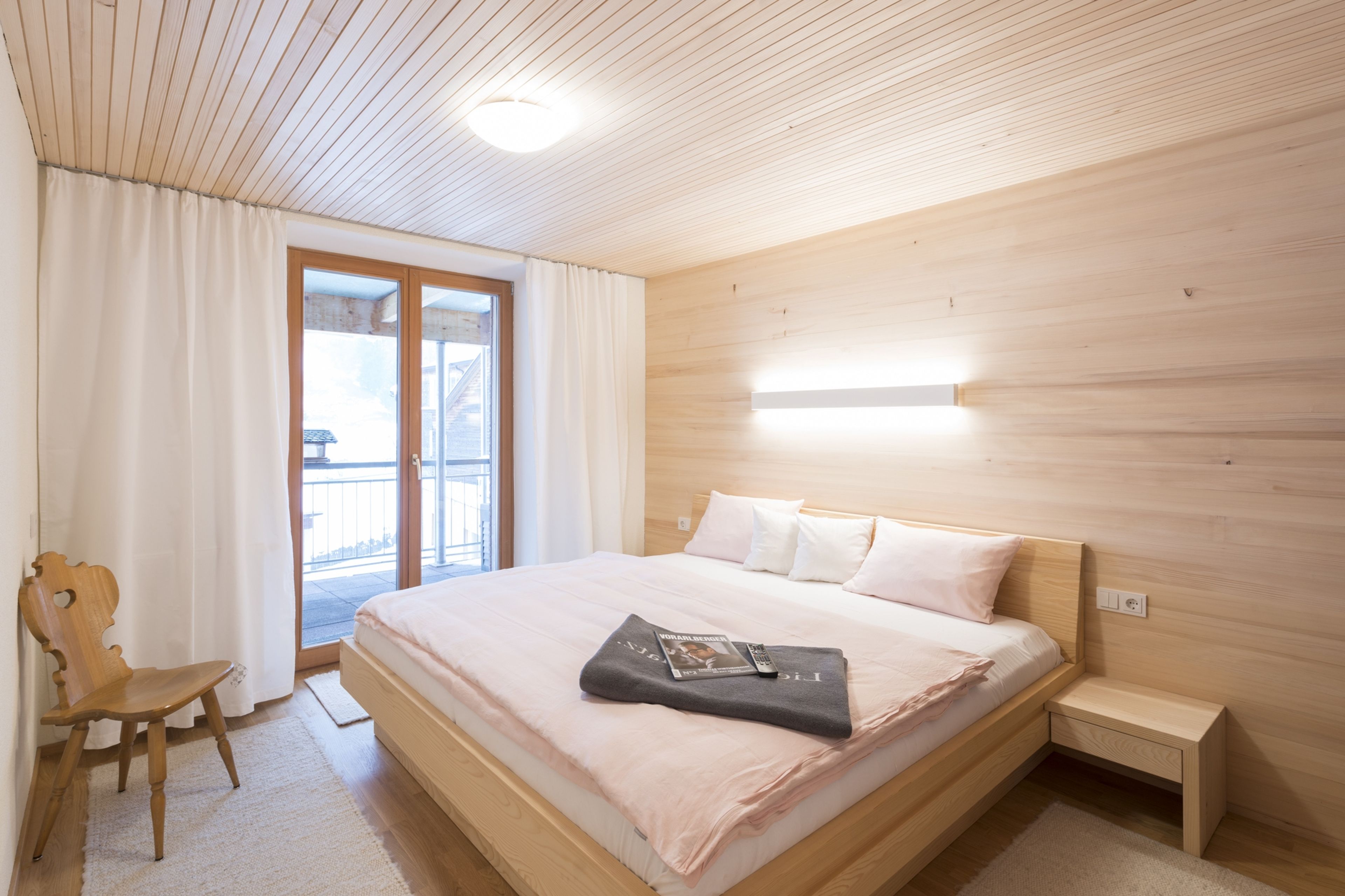 Doppelbett, Stuhl und Blick auf Terasse