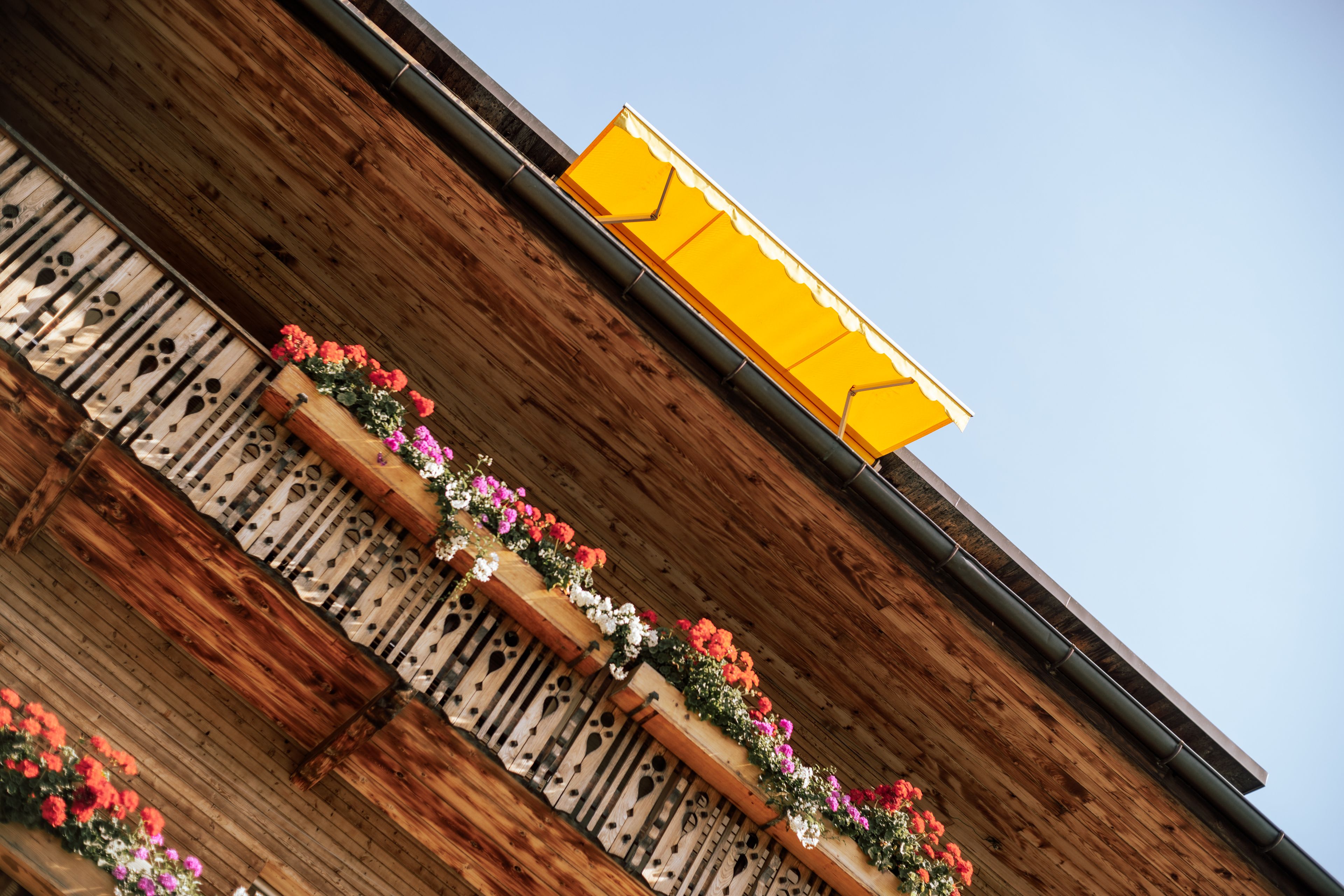 Balkone mit Blumen von unten und gelbe Jalousie
