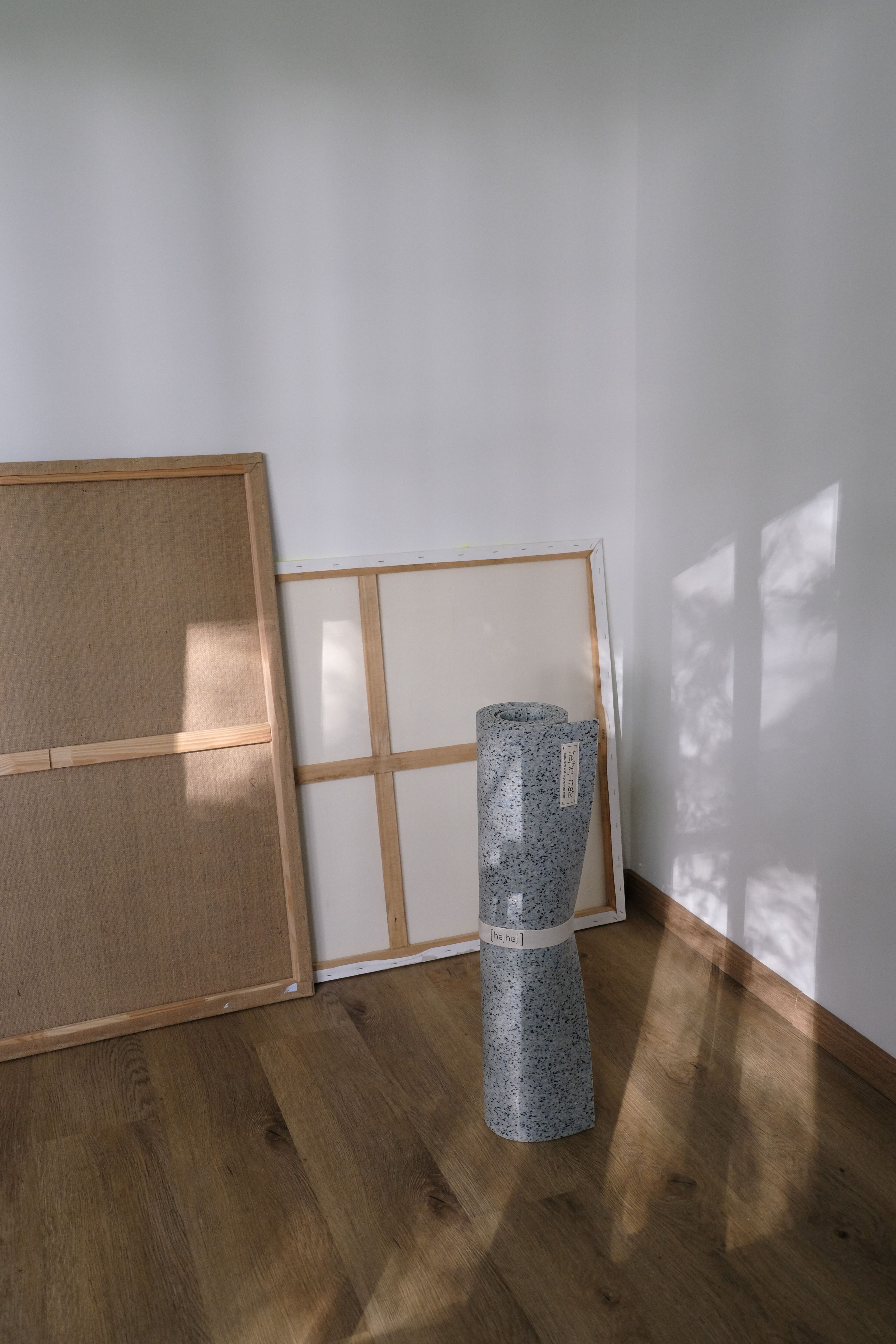 Zusammengerollte Yoga Mate vor weißer Wand und Bildleinwänder dahinter