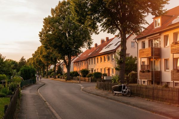 Gewachsene Wohnstrasse mit Solardaechern im Abendlicht - PV-Anlage nach 20 Jahren weiterbetreiben