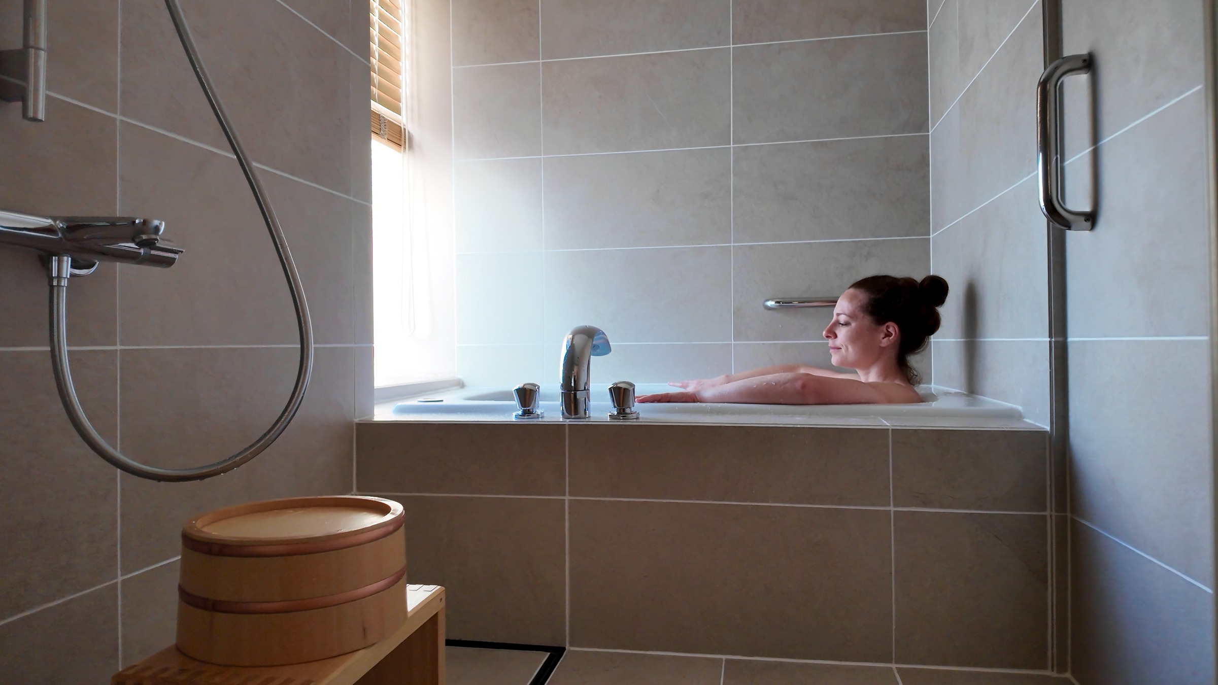 Krystal soaking in the bath at Takanawa Hanakohro with soft morning light through the window.