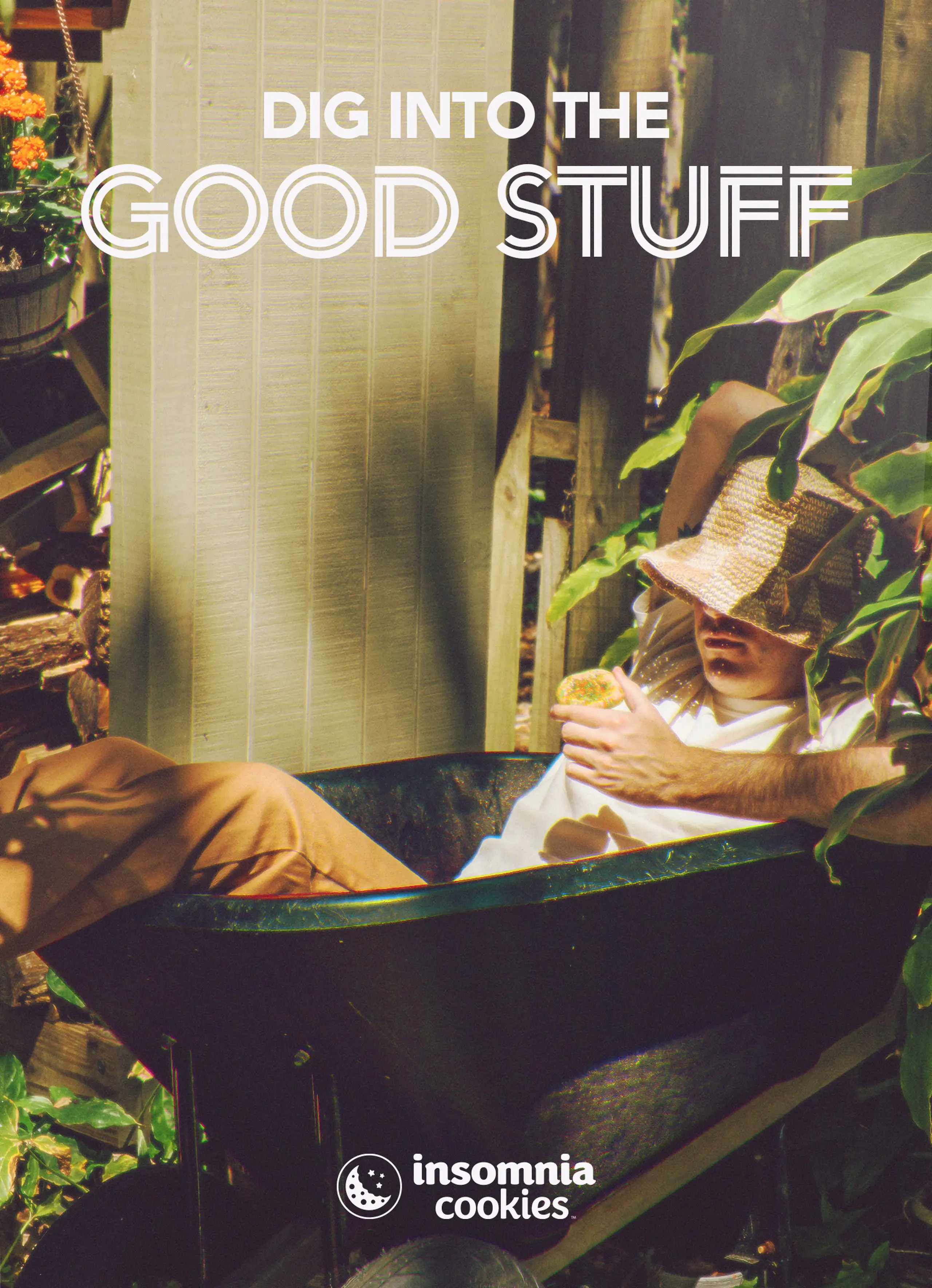 Guy laying in a wheel barrel eating an insomnia cookie