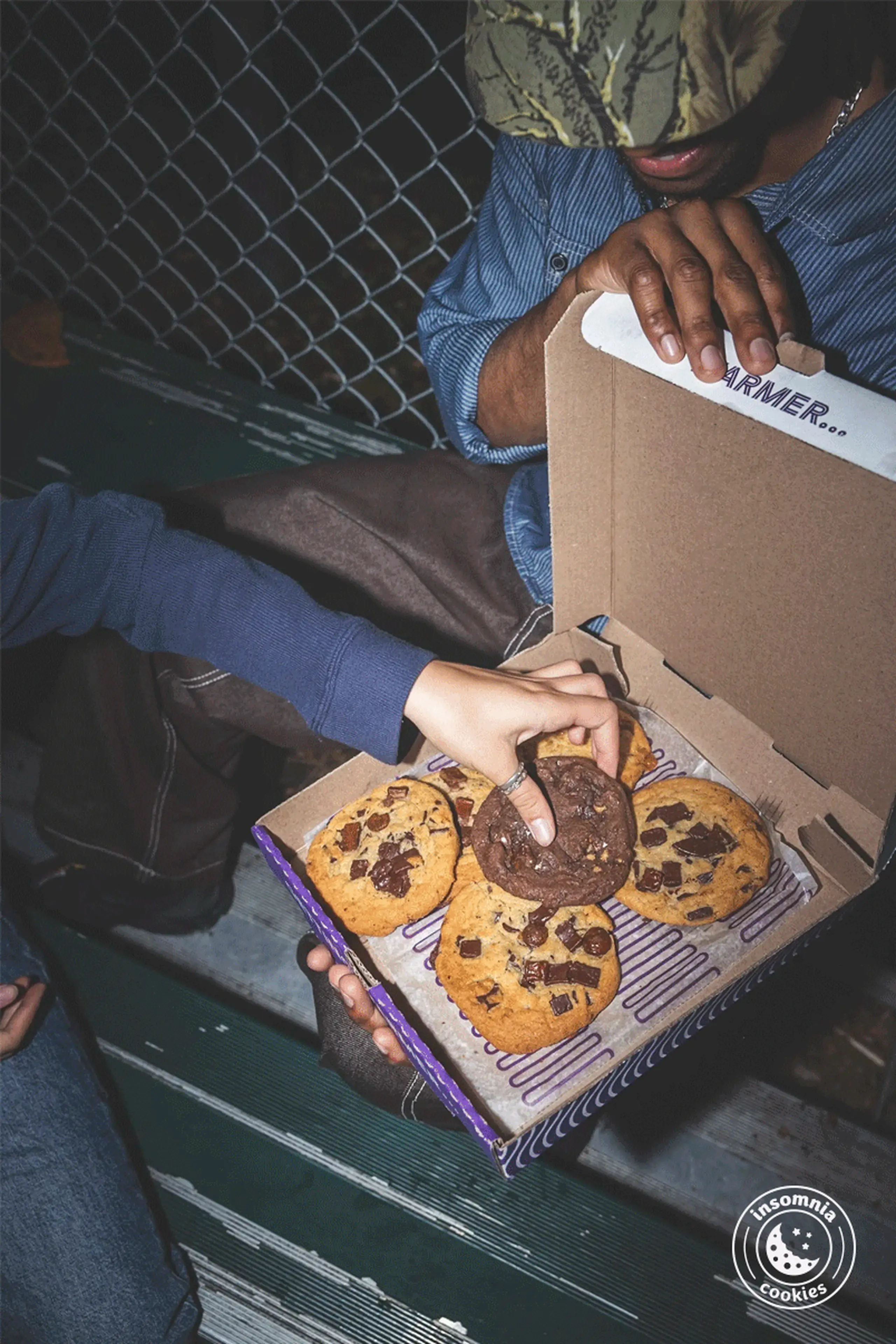 Girl picking up the double chocolate chunk insomnia cookie box.