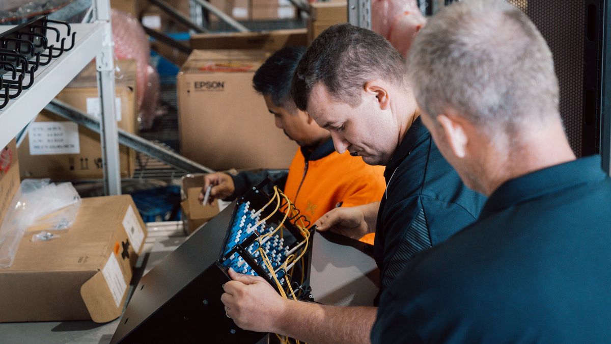 Three SHC team members inspecting a fibre patch panel