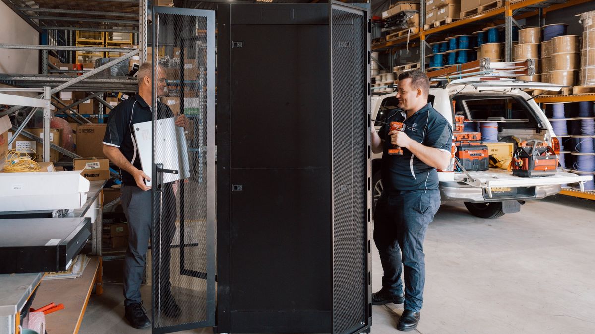 Two team members preparing a data cabinet in the warehouse