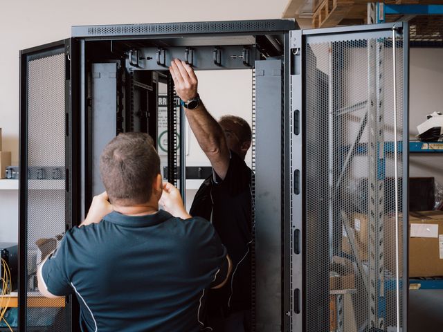 Two team members fitting out an open data rack